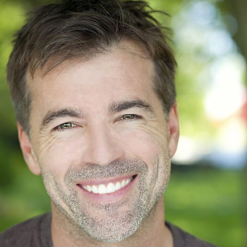 A man smiling for the camera in a park