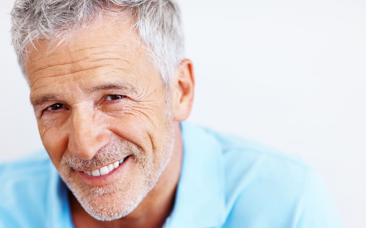 An older man smiling in a blue shirt